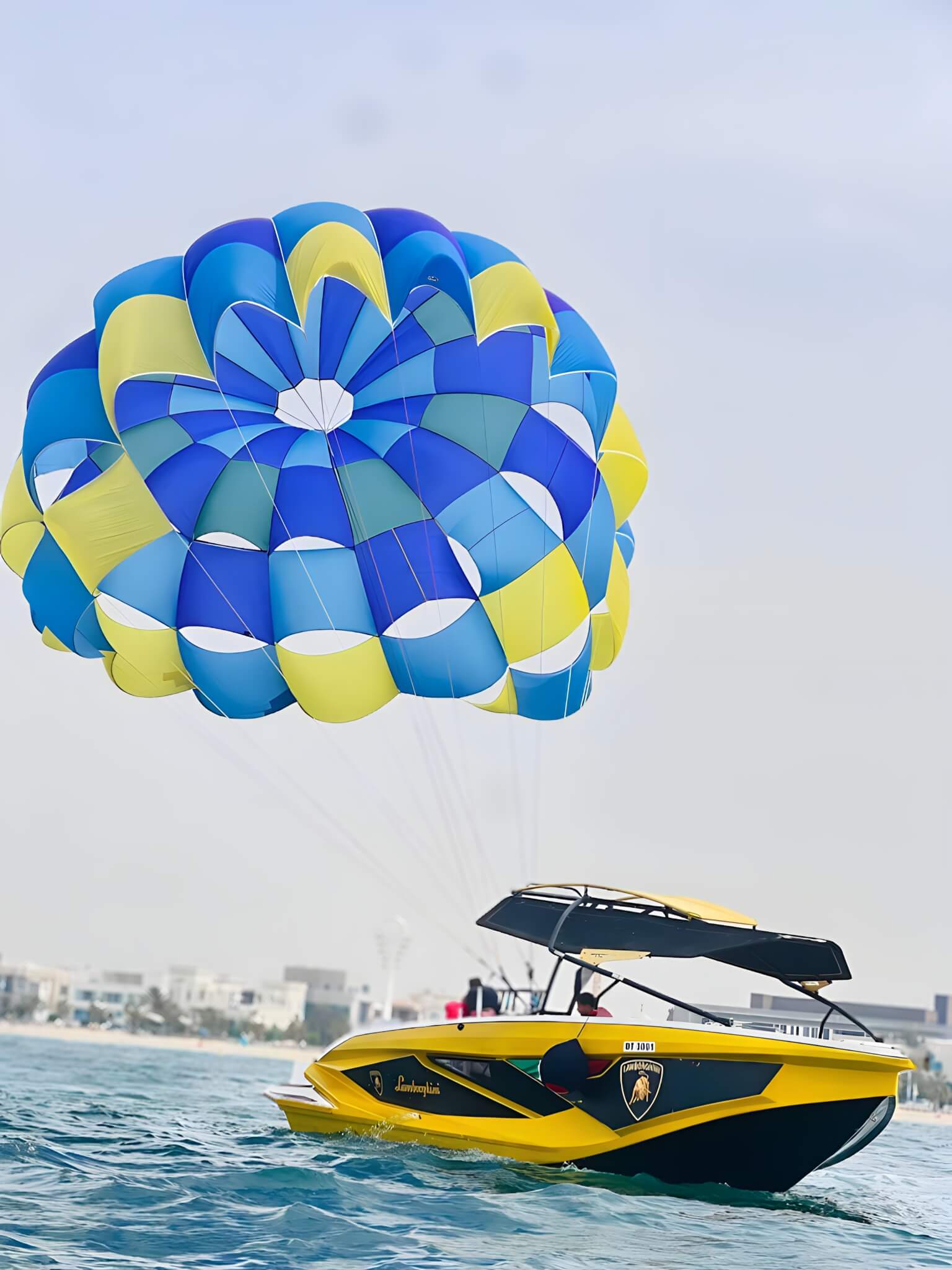 Colourful parasail above the Fun Beach Lamborghini speedboat on the Arabian Gulf in Dubai